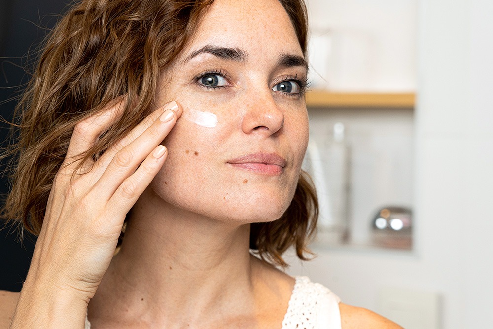 40 year old pretty woman applying skin moisturizer