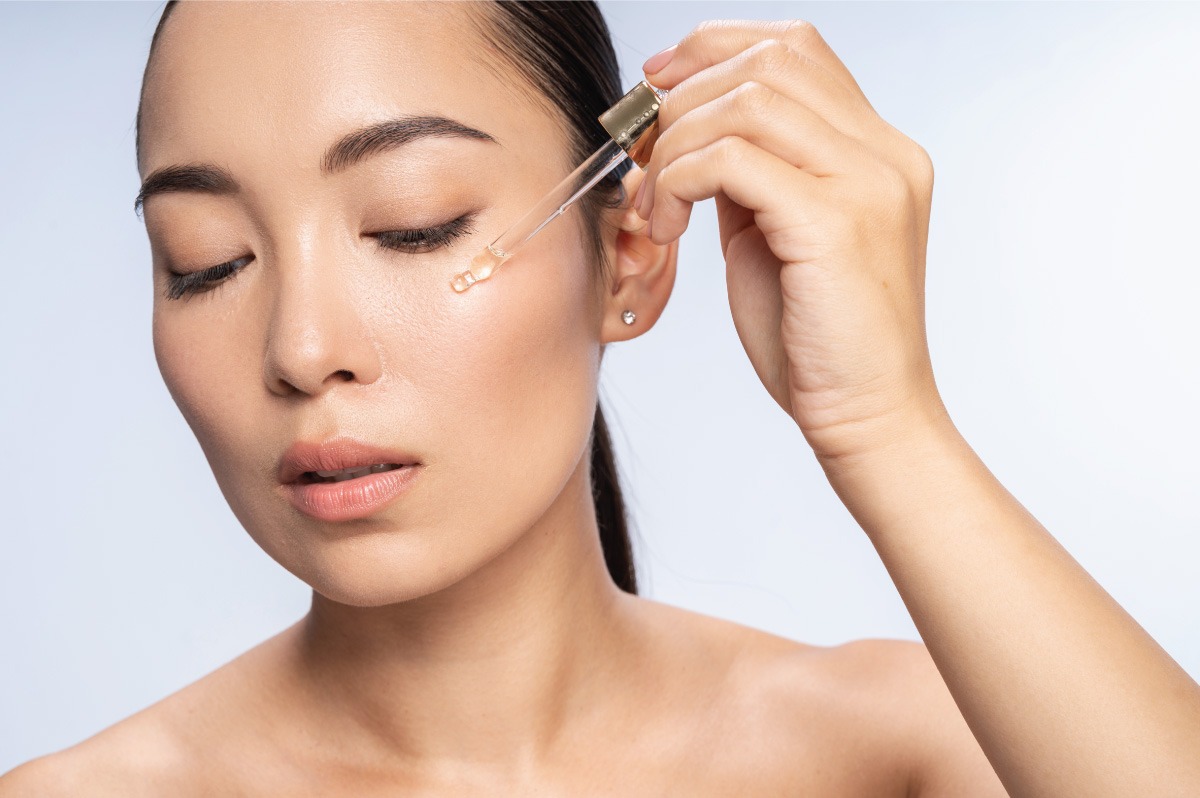 Beautiful asian woman applying a serum to her skin