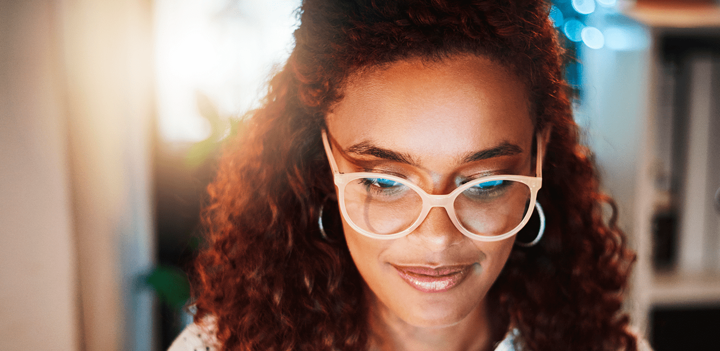 Black woman with glasses looking at a blue light screen