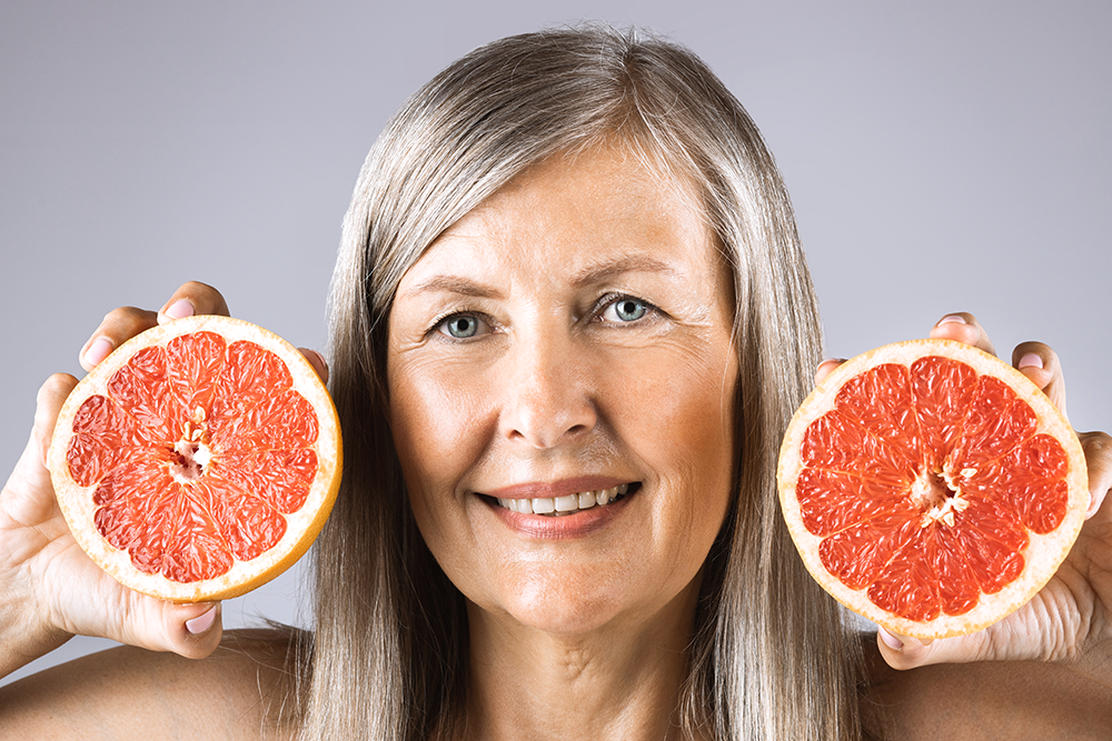 woman holding citrus fruit near her face